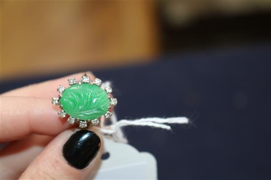 An 18ct white gold, carved oval cabochon jadeite and diamond set ring, size M.